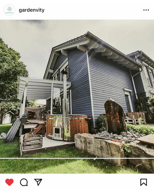 Round wooden hot tub integrated into a backyard with modern wooden decking and nearby home structures, illustrating customized outdoor installation.