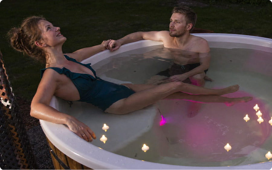 Zwei Personen entspannen in einem Hot Tub mit Kerzen und stimmungsvoller Beleuchtung