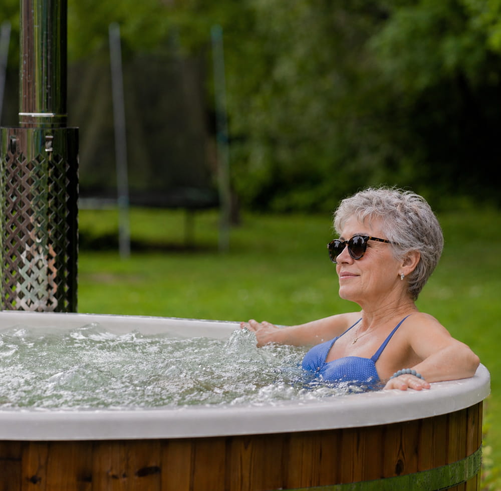 Frau entspannt in einem Hot Tub im Außenbereich mit grüner Umgebung im Hintergrund