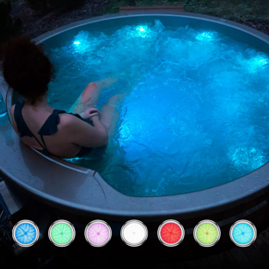 Abendansicht einer Person, die in einem beleuchteten runden Whirlpool mit blauen LED-Leuchten und sprudelndem Wasser entspannt.