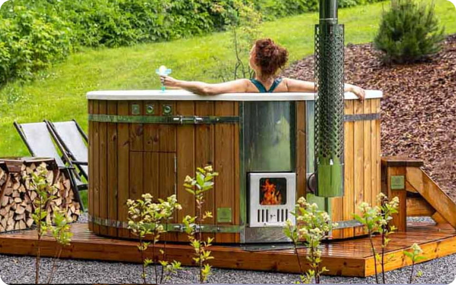 Frau entspannt in einem Hot Tub auf einer Holzterrasse im Garten