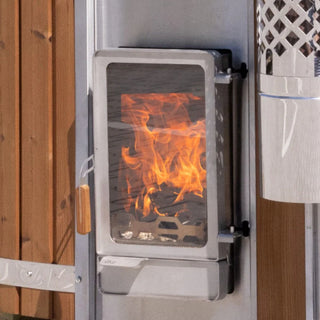 Close-up view of a wood-fired stove door with bright flames visible through a glass window panel