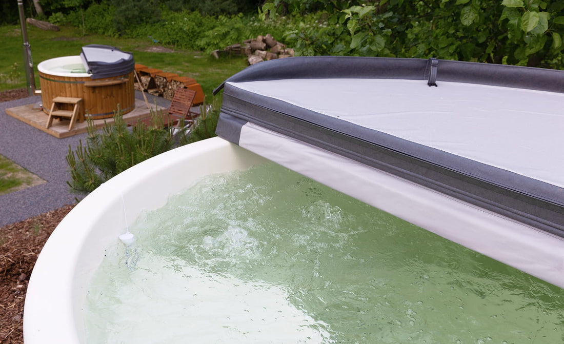 Hot tub with cover removed, showing water inside, in a garden setting.