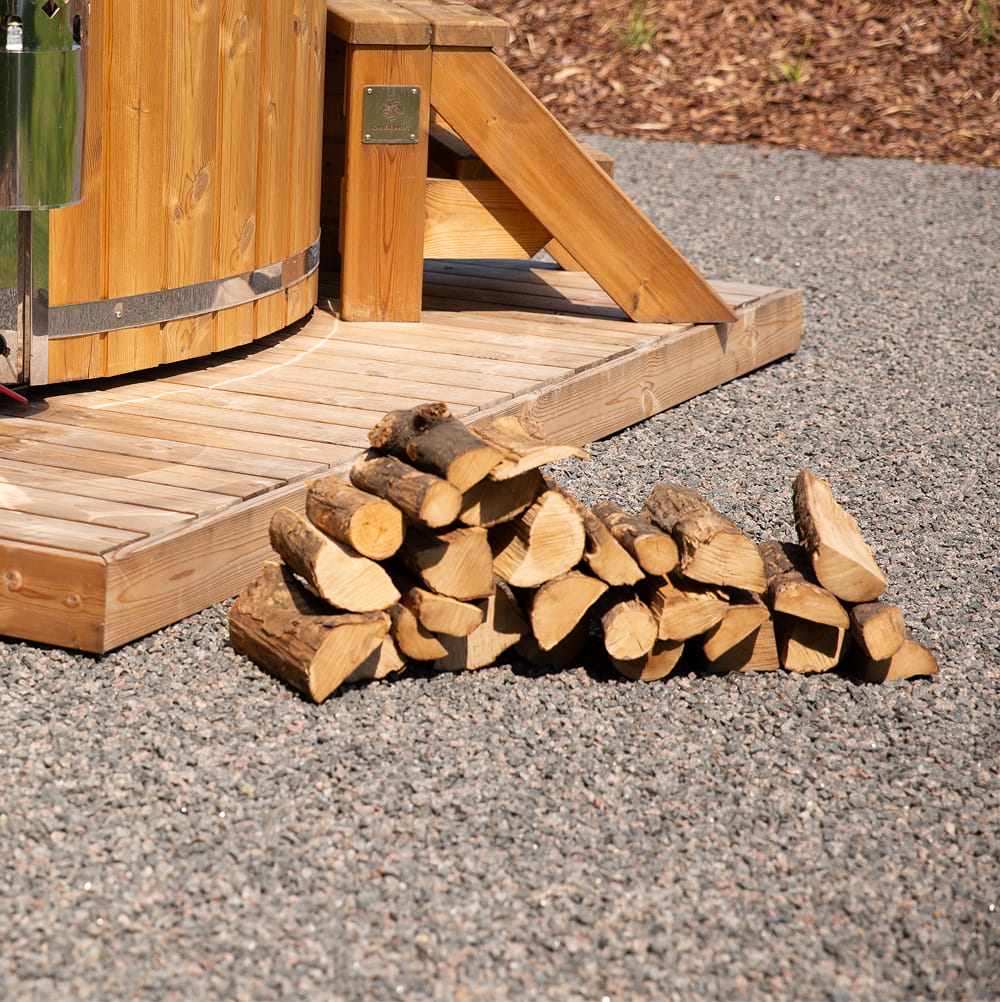Stapel Brennholz vor einer Holzkonstruktion auf einer Kiesfläche