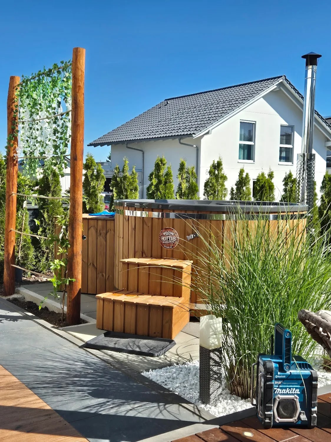 Gardenvity Holzofen-hot tub in einem privaten Garten mit Holztreppe und Grünanlagen installiert.