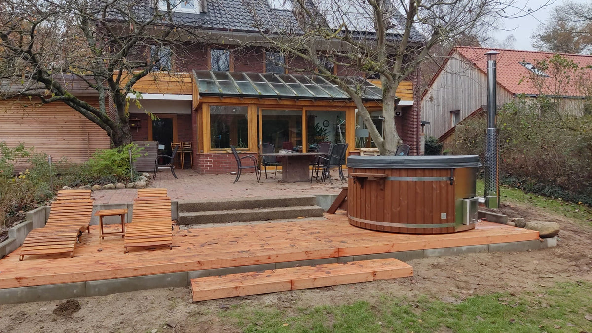 Gardenvity Holzofen-Whirlpool auf Holzterrasse in einem rustikalen Hinterhof mit Backsteinhaus